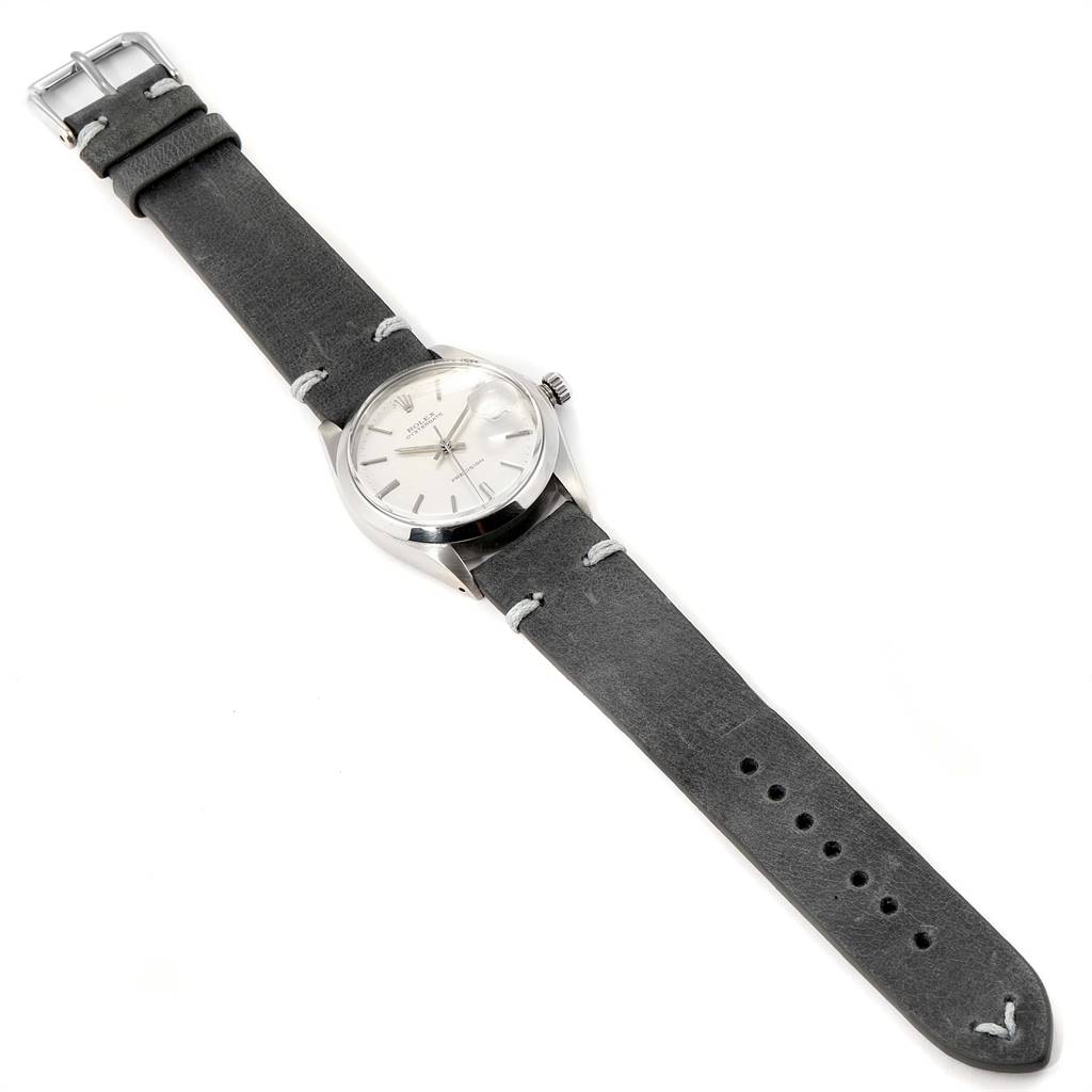 The image shows a Rolex Vintage Collection 6694 Men
s Stainless Steel Silver Dial 6694 Men
s Stainless Steel Silver Dial watch, featuring a grey leather strap, silver case, and white dial, viewed from an overhead angle.