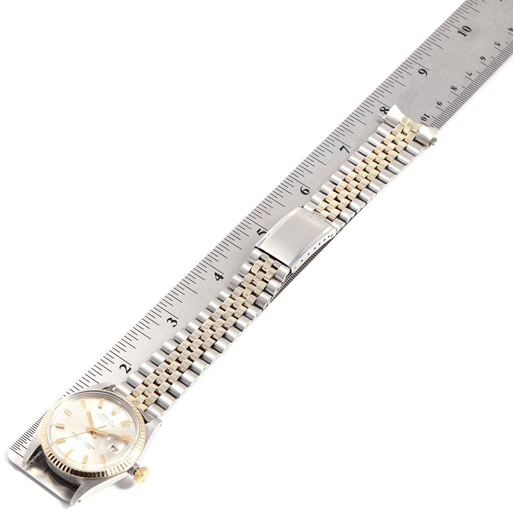 The Rolex Vintage Collection 1601 Men
s Stainless Steel Silver Dial 1601 Men
s Stainless Steel Silver Dial model watch is shown from a top-down view, displaying the face, bracelet, and clasp next to a ruler.