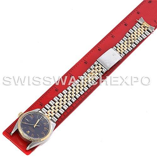 The image shows the Rolex Vintage Collection 16013 Men's Stainless Steel Blue Dial 16013 Men's Stainless Steel Blue Dial watch laid flat alongside a red measuring tool, showcasing its bracelet and face.