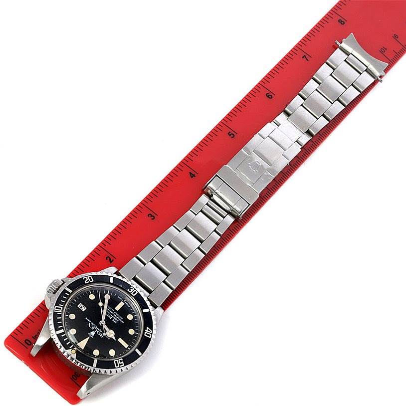 The Rolex Vintage Collection 1665 Men's Stainless Steel  1665 Men's Stainless Steel  watch is shown from a top-down angle, displaying the face, bezel, and entire bracelet on a red ruler.