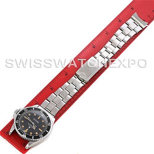 This image shows a top view of a Rolex Vintage Collection 5513 Men's Stainless Steel Black Dial 5513 Men's Stainless Steel Black Dial watch along with its stainless steel bracelet, next to a red-measuring ruler.