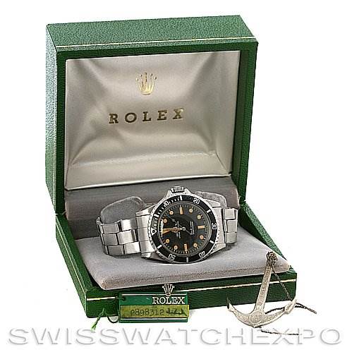 The image shows a front view of a Rolex Vintage Collection 5513 Men's Stainless Steel Black Dial 5513 Men's Stainless Steel Black Dial watch in its branded box with a tag and an anchor pendant accessory.