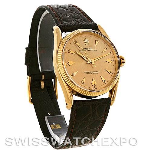 The image shows a side angle of a Rolex Vintage Collection 1011 Men's Yellow Gold Champagne Dial 1011 Men's Yellow Gold Champagne Dial watch, highlighting its gold dial, brown leather strap, and fluted bezel.