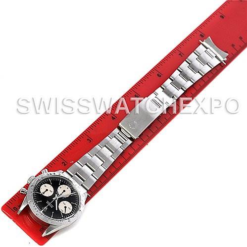 The image shows a top-down view of a Vintage Collection Rolex watch with a metal bracelet and a black and white dial placed on a red ruler.