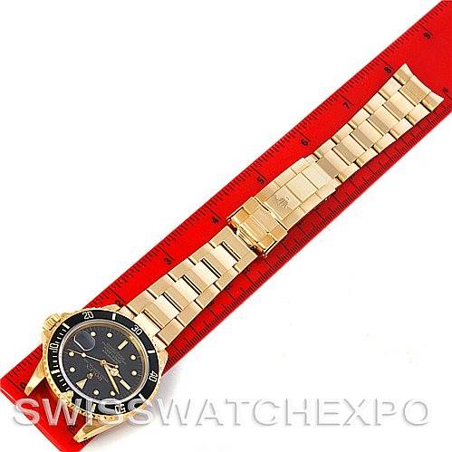 The Rolex Vintage Collection 16808 Men's Yellow Gold Black Dial 16808 Men's Yellow Gold Black Dial watch is shown from a top-down angle lying flat with the entire band and face visible next to a red ruler.