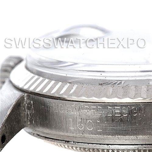 A close-up of the side view of a Rolex Vintage Collection 1601 Men's Stainless Steel Grey Dial 1601 Men's Stainless Steel Grey Dial watch, showing part of the bezel, crystal, and engravings.
