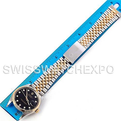 This image shows a Rolex Vintage Collection 16013 Men's Stainless Steel Black Dial 16013 Men's Stainless Steel Black Dial watch with a black dial, gold bezel, and two-tone bracelet laid flat against a ruler.