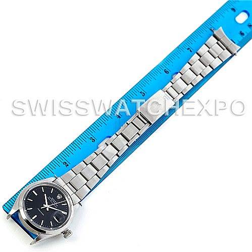 The image shows the Rolex Vintage Collection 5700 Men
s Stainless Steel Black Dial 5700 Men
s Stainless Steel Black Dial watch laid out flat against a blue ruler, displaying the face, bracelet, and clasp.