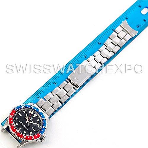 The Rolex Vintage Collection 1675 Men's Stainless Steel Black Dial 1675 Men's Stainless Steel Black Dial watch is shown from a top-down angle, displaying its bezel, face, strap, and clasp against a blue ruler.