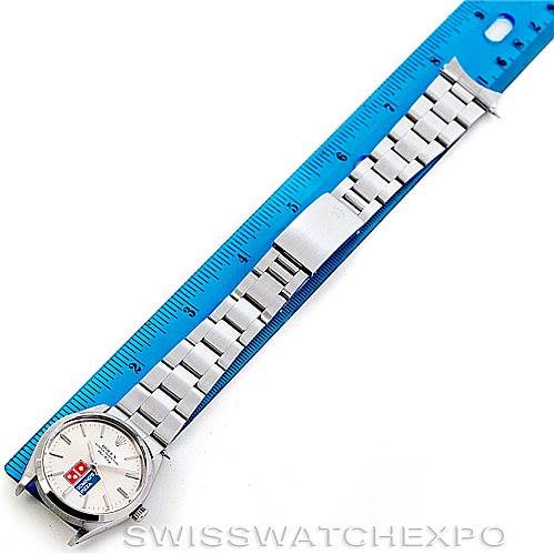 The image shows an overhead view of a Rolex Vintage Collection 5500 Men's Stainless Steel Silver Dial 5500 Men's Stainless Steel Silver Dial model watch, revealing its face, bracelet, and clasp beside a blue ruler.