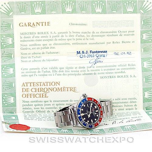 The image shows a front view of a Vintage Collection Rolex watch with a blue and red bezel, placed on top of its warranty certificate.