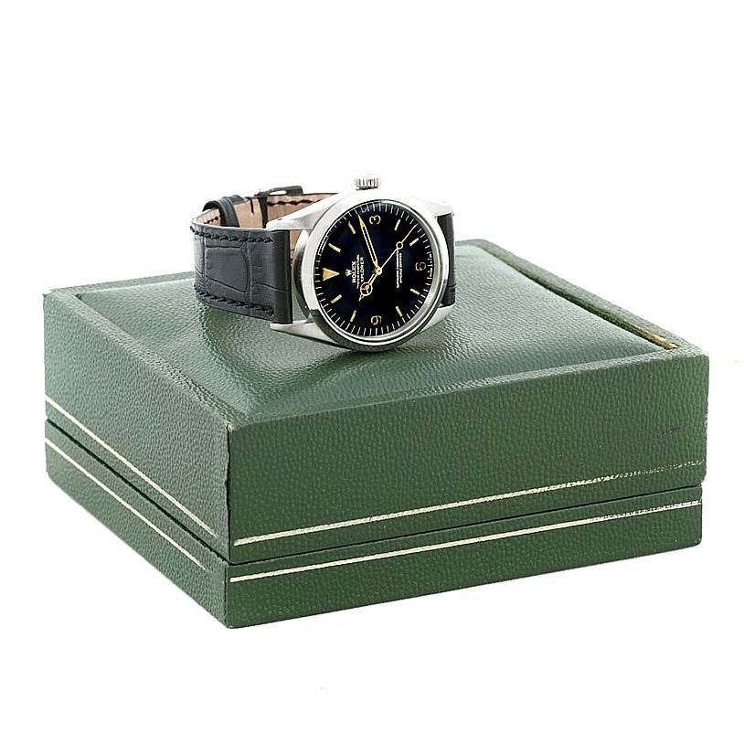 The image shows a side angle view of a Rolex Vintage Collection 1016 Men's Stainless Steel Black Dial 1016 Men's Stainless Steel Black Dial watch with a black leather strap and a green box.