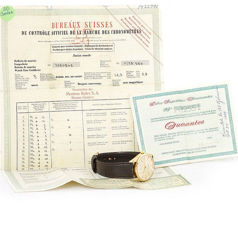 The image shows a Rolex Vintage Collection 1003 Yellow Gold Silver Dial 1003 Yellow Gold Silver Dial model watch placed on top of its official documents and a guarantee certificate.