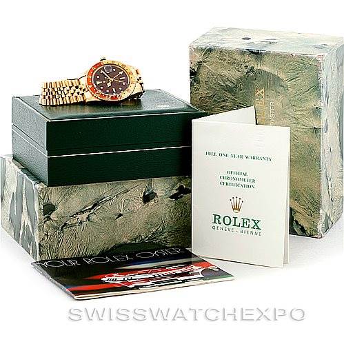 The image shows a Rolex Vintage Collection 1675 Men's Yellow Gold Brown Dial 1675 Men's Yellow Gold Brown Dial watch with its box, a warranty booklet, and a user manual at an angled view.