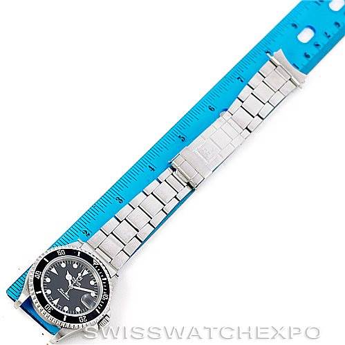 The image shows a Tudor Submariner 79190 Men's Stainless Steel Black Dial 79190 Men's Stainless Steel Black Dial watch laid flat on a blue measuring ruler, displaying its face, bezel, and metal bracelet.