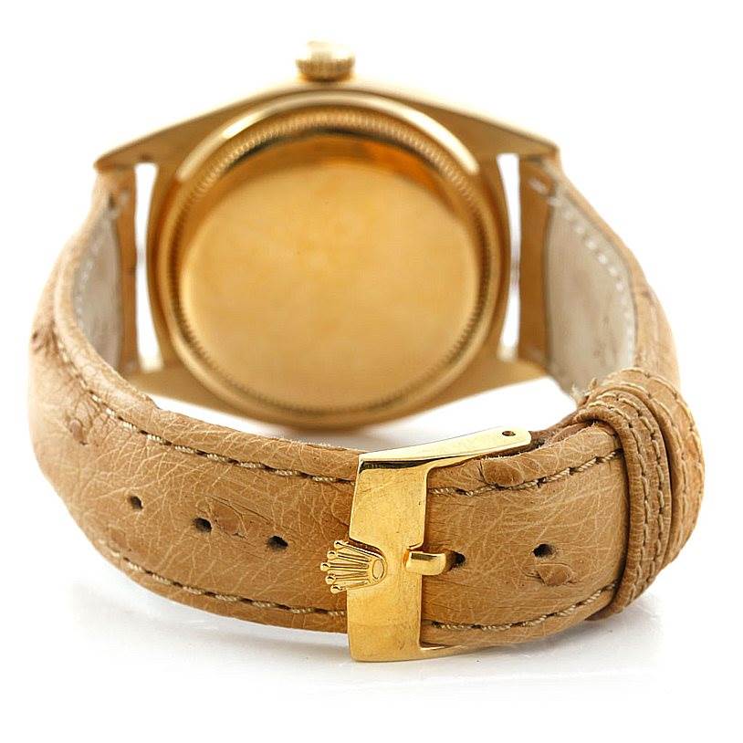 The image shows the back of the Rolex Vintage Collection 6605 Men's Yellow Gold Silver Dial 6605 Men's Yellow Gold Silver Dial watch and its leather strap with a gold clasp.