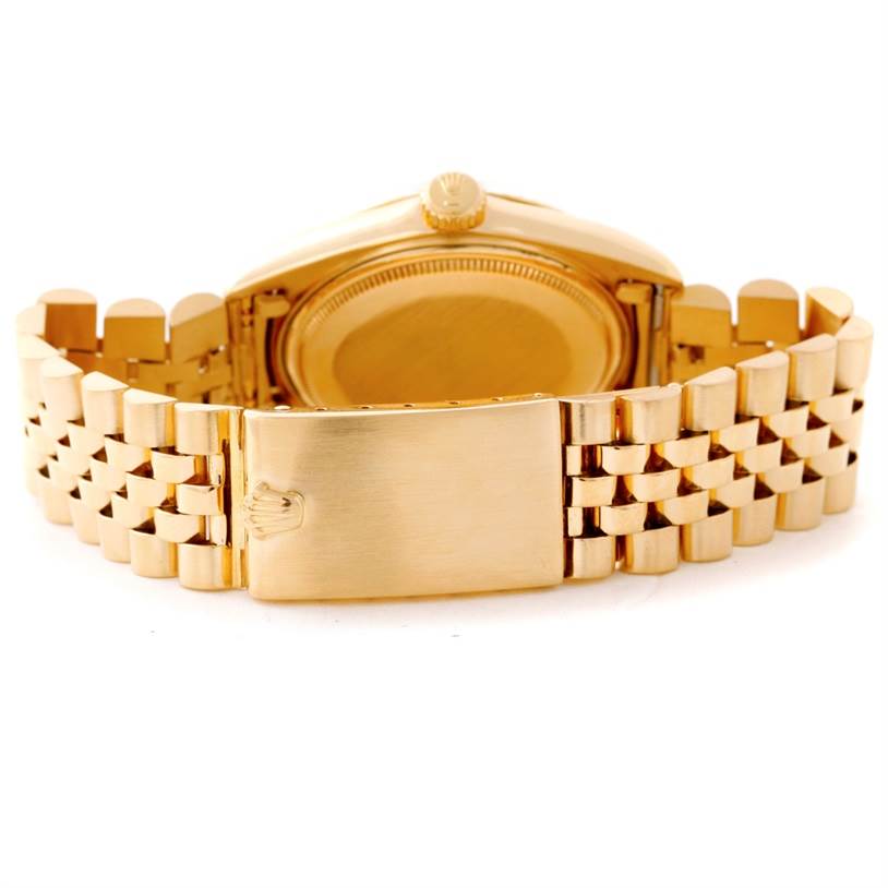 The image shows the back view of a Rolex Vintage Collection 1601 Men's Yellow Gold Silver Dial 1601 Men's Yellow Gold Silver Dial watch, highlighting its gold case and bracelet with a clasp.