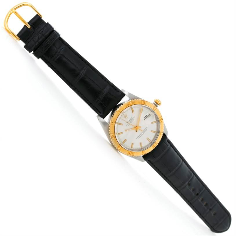 The Rolex Vintage Collection 1625 Men's Steel and Gold (two tone) Silver Dial 1625 Men's Steel and Gold (two tone) Silver Dial watch is shown from a top-down angle, displaying the face, gold bezel, crown, and black leather strap.