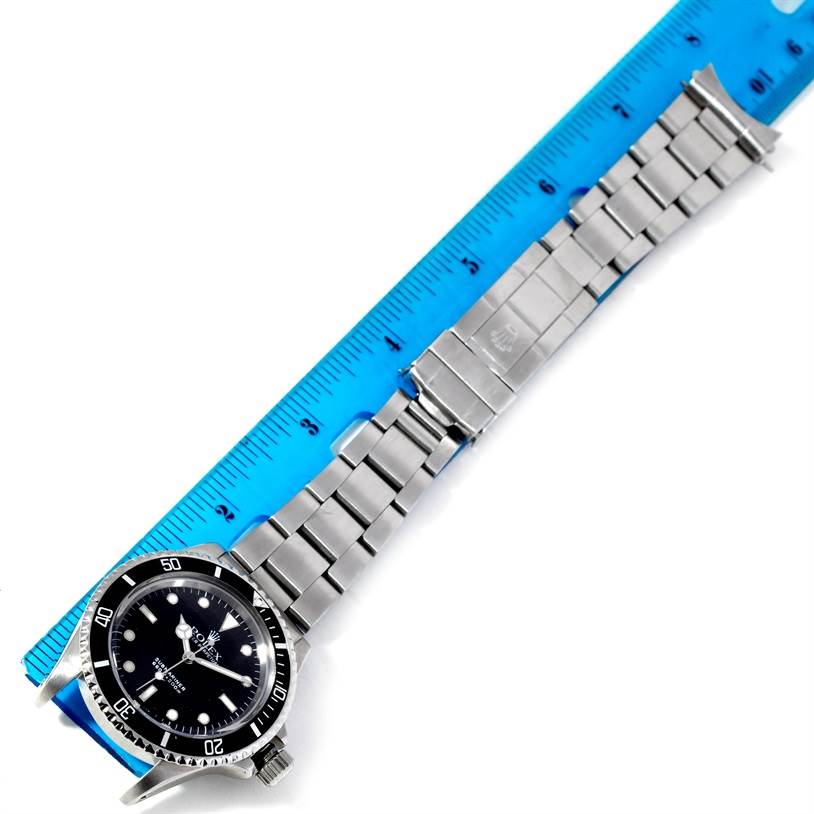 The image shows a Rolex Vintage Collection 5513 Men's Stainless Steel Black Dial 5513 Men's Stainless Steel Black Dial watch positioned alongside a blue ruler, displaying its face and bracelet.