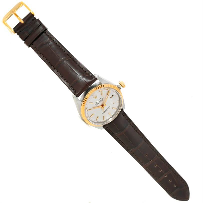 The Rolex Vintage Collection 1601 Men's Stainless Steel Silver Dial 1601 Men's Stainless Steel Silver Dial watch is shown from a top-down angle, featuring a brown leather strap, a gold bezel, and a silver dial.