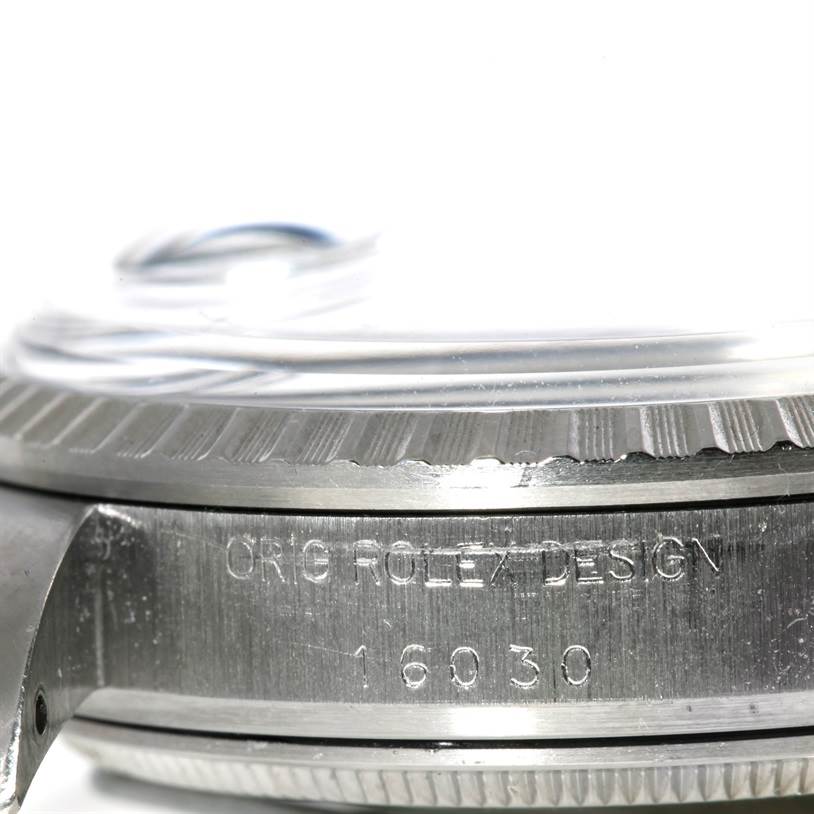 The image shows a close-up side view of the Rolex Vintage Collection 16030 Men's Stainless Steel White Dial 16030 Men's Stainless Steel White Dial model watch's case, revealing part of the bezel and engraved details.