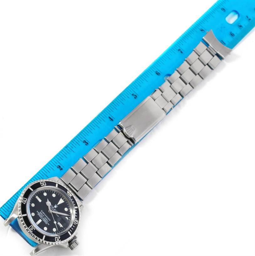 The Rolex Vintage Collection 1680 Men's Stainless Steel Black Dial 1680 Men's Stainless Steel Black Dial model is shown face-up with a metal band extended alongside a blue ruler.