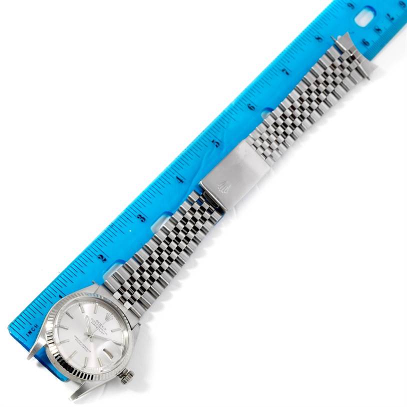 The image shows a Rolex Vintage Collection 1601 Men's Stainless Steel Silver Dial 1601 Men's Stainless Steel Silver Dial watch laid flat next to a blue ruler, displaying its face and metal bracelet.