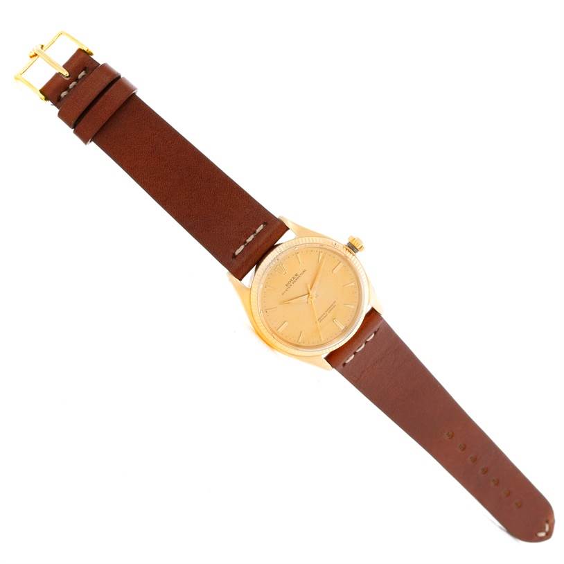 The image shows a Rolex Vintage Collection 1005 Men's Yellow Gold Champagne Dial 1005 Men's Yellow Gold Champagne Dial watch from a top-down angle, displaying its dial, case, and leather strap.