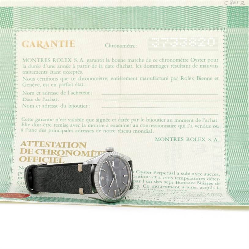 The image shows a Rolex Vintage Collection 1603 Men's Stainless Steel Grey Dial 1603 Men's Stainless Steel Grey Dial watch placed sideways on its warranty certificate.