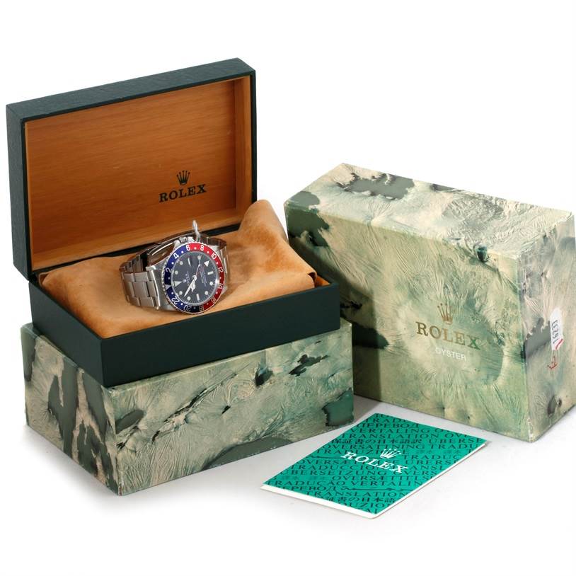 The image shows a Rolex Vintage Collection 1675 Men's Stainless Steel Black Dial 1675 Men's Stainless Steel Black Dial watch in an open box, with accompanying packaging and a booklet displayed beside it.