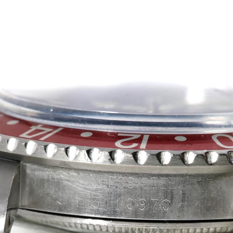 The image shows a close-up of the side and bezel of a Vintage Collection Rolex watch, highlighting the red bezel and stainless steel case.