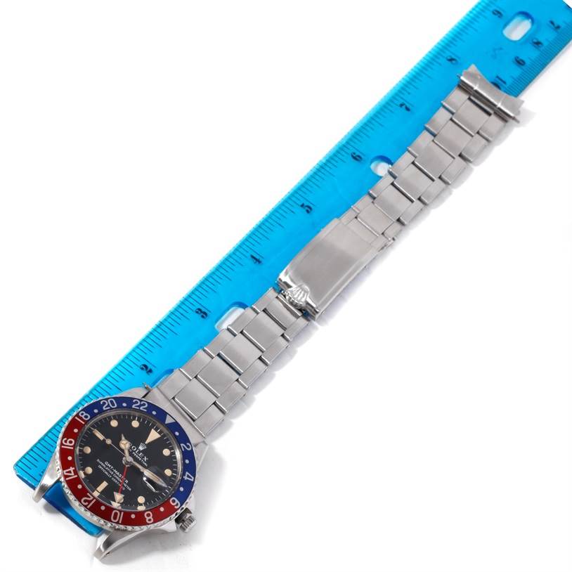 The image shows a Vintage Collection Rolex watch laying flat next to a blue ruler, displaying its face and metal link bracelet.