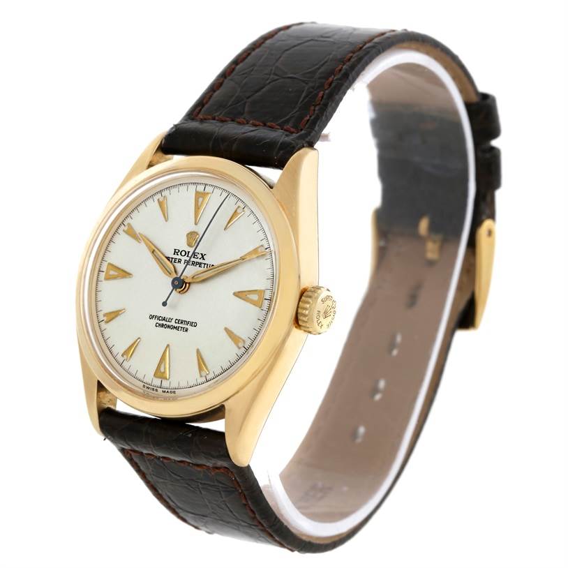 This image shows a Rolex Vintage Collection 6084 Men's Yellow Gold Silver Dial 6084 Men's Yellow Gold Silver Dial watch at an angled side view, highlighting its gold casing, white dial, and black leather strap.