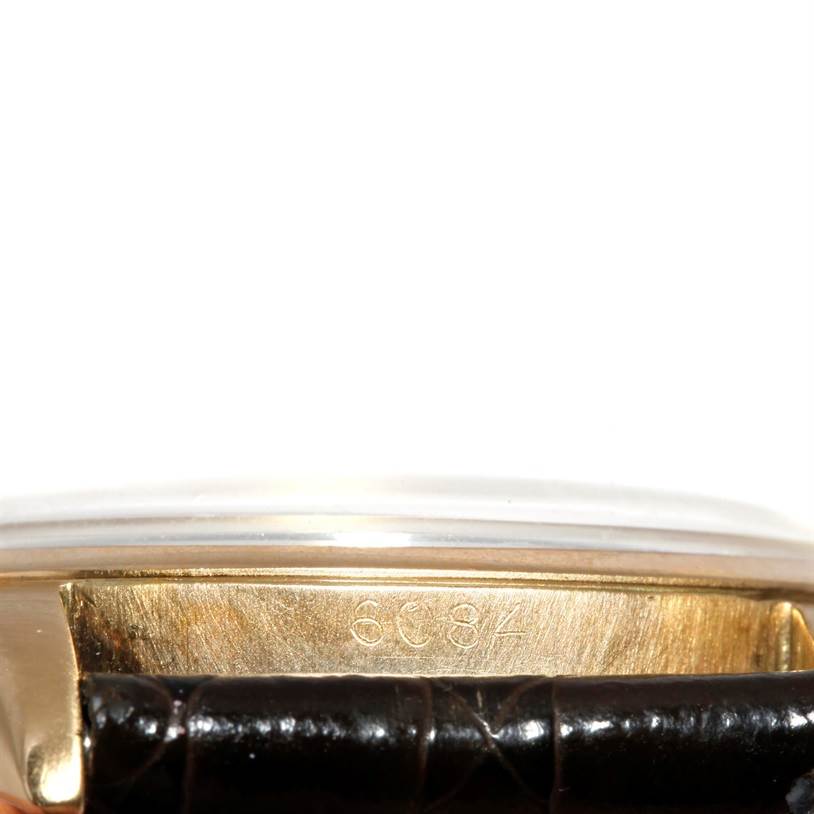 This image shows a close-up of the case's serial number and the leather strap attachment of a Rolex Vintage Collection 6084 Men's Yellow Gold Silver Dial 6084 Men's Yellow Gold Silver Dial watch.