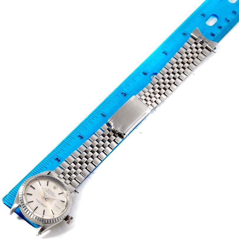 The image shows the full length of a Rolex Vintage Collection 1601 Stainless Steel Silver Dial 1601 Stainless Steel Silver Dial watch, laid next to a blue ruler, displaying its face and metal bracelet.