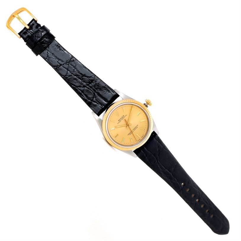 The image shows a bird's-eye view of a Vintage Collection Rolex watch with a gold dial and black leather strap.