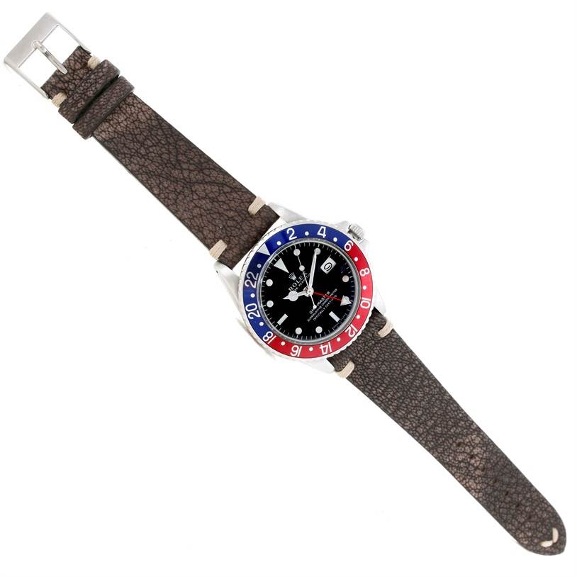 The image shows a fully extended Rolex Vintage Collection 1675 Men's Stainless Steel Black Dial 1675 Men's Stainless Steel Black Dial watch from a top-down view, displaying its dial, bezel, and leather strap.