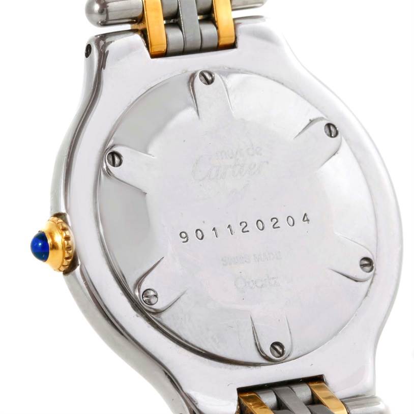 The image shows the back of a Must 21 Cartier watch, highlighting the case back, crown, and part of the bracelet.