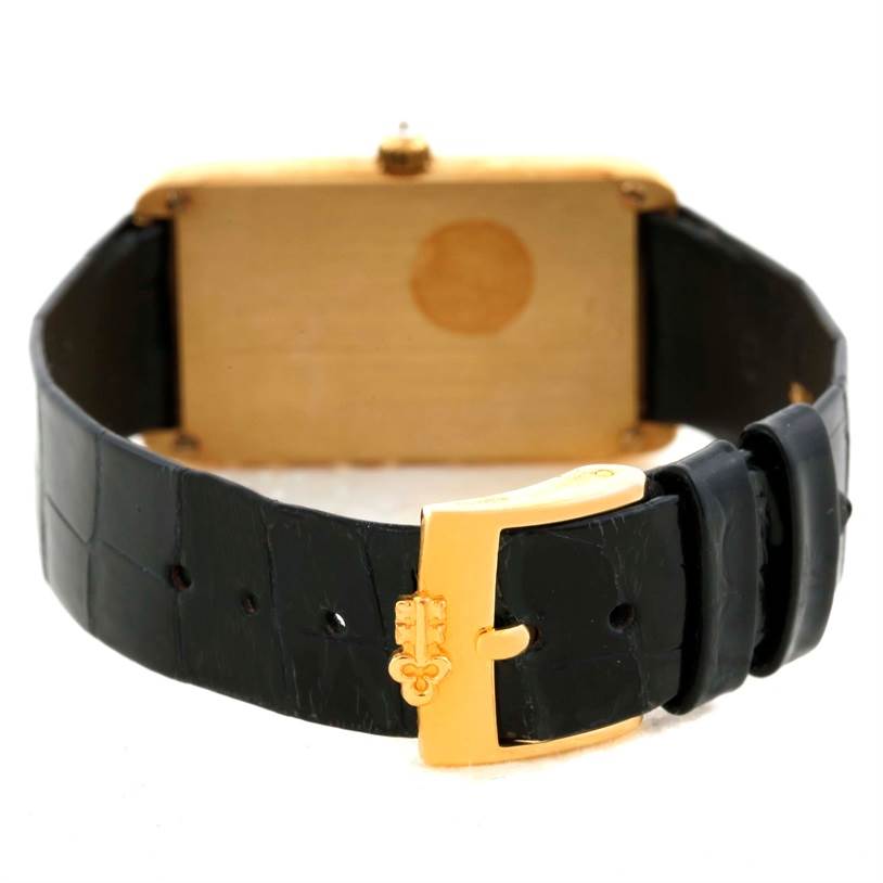 The image shows the backside of a Corum Women's Yellow Gold Champagne Dial Women's Yellow Gold Champagne Dial 18K Yellow Gold Diamond 5 Gram Ingot 999.9 Watch with a black leather strap and gold buckle.