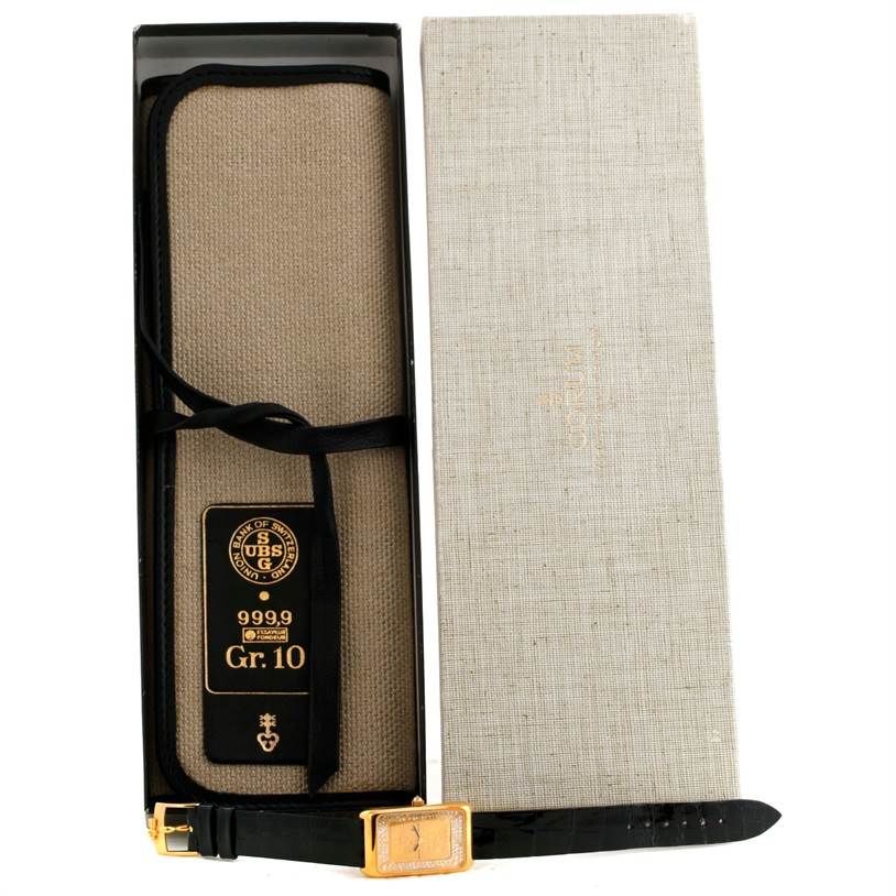 The image shows an open box containing a Corum Women's Yellow Gold Champagne Dial Women's Yellow Gold Champagne Dial 18K Yellow Gold Diamond 5 Gram Ingot 999.9 Watch with its strap and protective pouch.