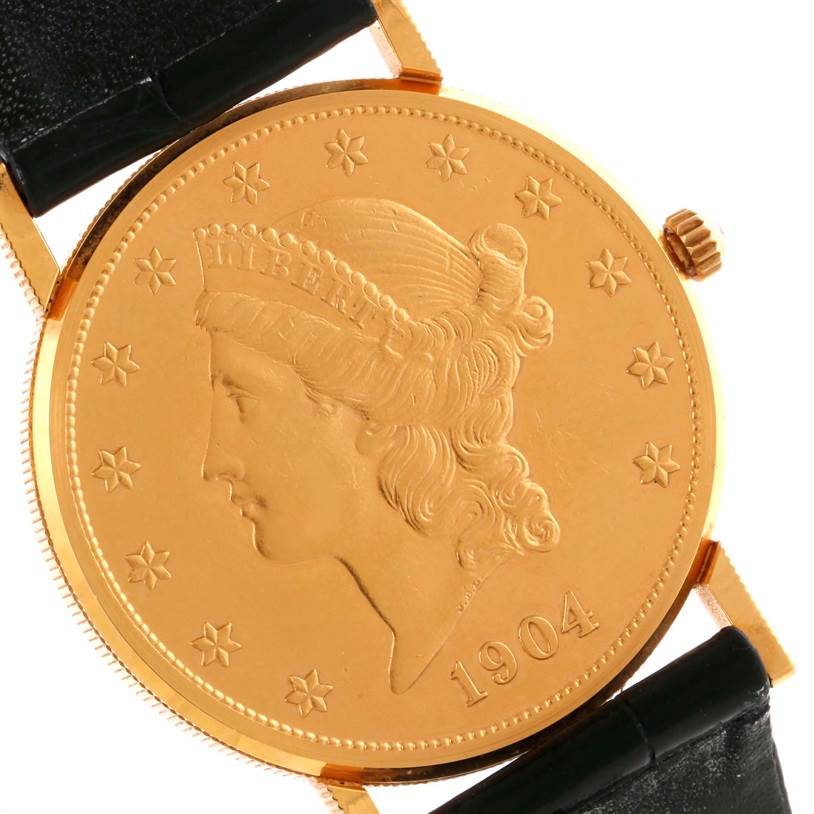 The image shows a close-up of the dial and crown of the Corum Coin Watch 4414556 Men
s Yellow Gold Black Dial 4414556 Men
s Yellow Gold Black Dial model, featuring a coin with the year 1904.