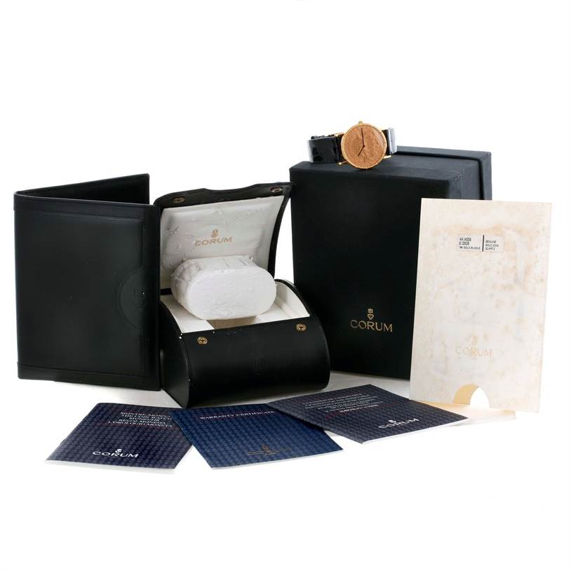 The image shows the Coin Watch model by Corum along with its box, case, and accompanying documents.
