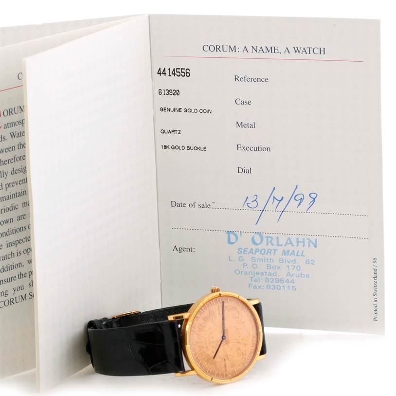 The image shows a Corum Coin Watch 4414556 Men
s Yellow Gold Black Dial 4414556 Men
s Yellow Gold Black Dial model, partially visible from the front, accompanied by its documentation book.