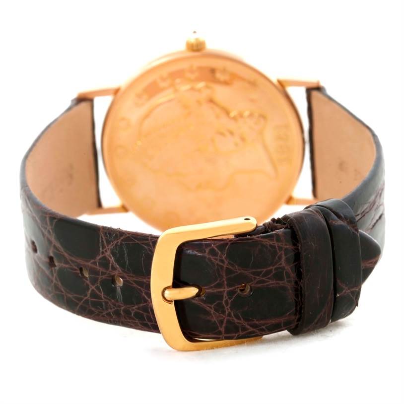 This image shows the back side of a Corum Coin Watch Men's Yellow Gold Black Dial Men's Yellow Gold Black Dial, featuring the leather strap and golden buckle.