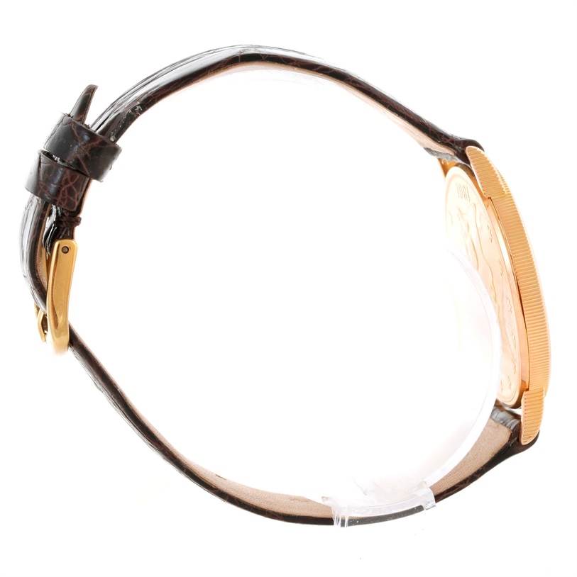 The image shows a side view of a Corum Coin Watch Men's Yellow Gold Black Dial Men's Yellow Gold Black Dial model, highlighting its leather strap and gold bezel.