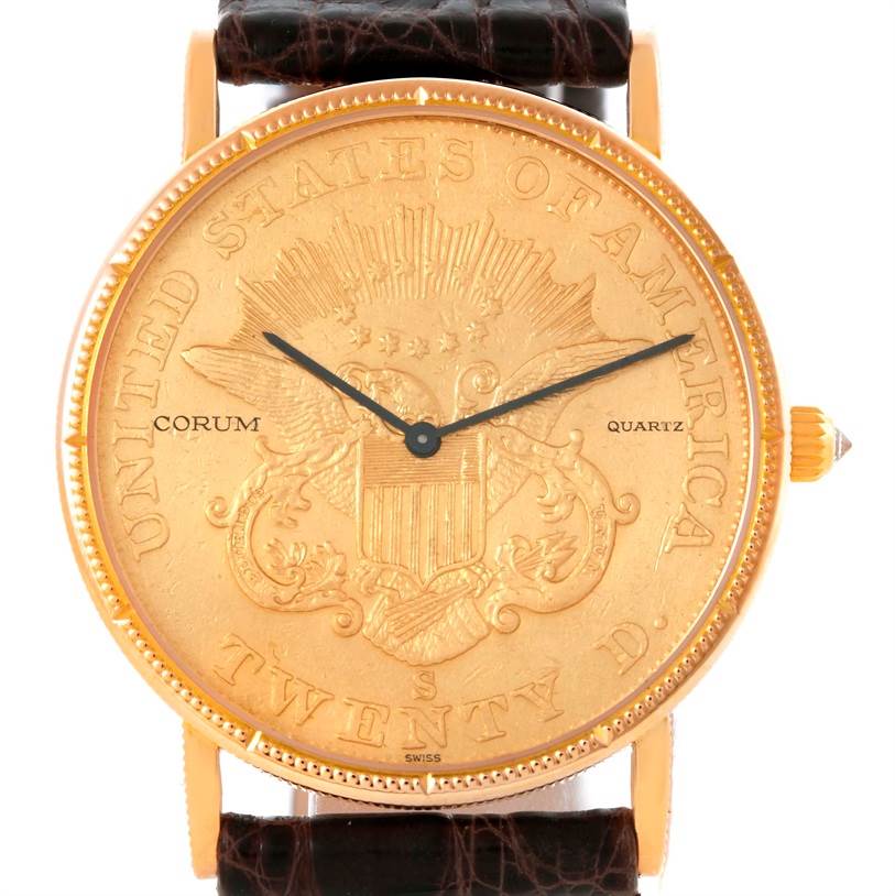 The image shows a front view of a Corum Coin Watch Men's Yellow Gold Black Dial Men's Yellow Gold Black Dial model, displaying its face, bezel, hands, and parts of the strap.