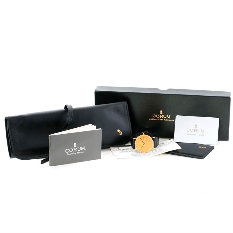 The image shows a Corum Coin Watch Men
s Yellow Gold Black Dial Men
s Yellow Gold Black Dial model with its box, warranty card, operating manual, and a black watch roll.