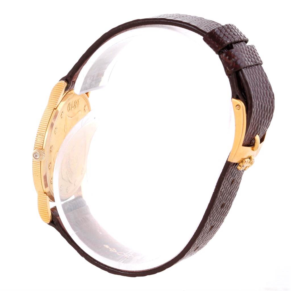 The image shows a side view of the Corum Women's Yellow Gold Black Dial Women's Yellow Gold Black Dial 18K Yellow Gold 10 Dollars Coin Diamond Ladies Watch, highlighting its gold case, brown strap, and buckle.