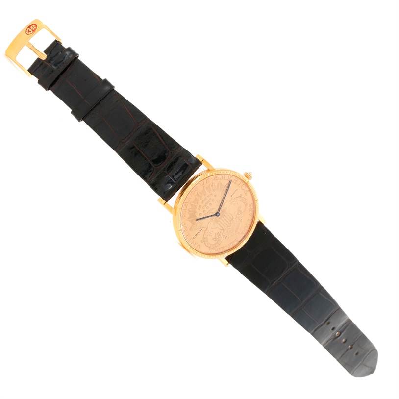 The image shows a top-down view of the Corum Coin Watch Men's Yellow Gold Black Dial Men's Yellow Gold Black Dial model, displaying both the watch face and the black strap.