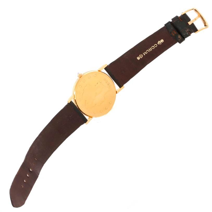 The Corum Coin Watch Men's Yellow Gold Black Dial Men's Yellow Gold Black Dial model is shown from an angled top-down view, displaying its gold coin dial and brown leather strap.